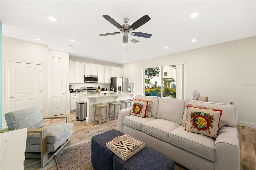 A living room with a sofa, armchair, and kitchen island with bar stools — 8205 SURF STREET, KISSIMMEE, FL
