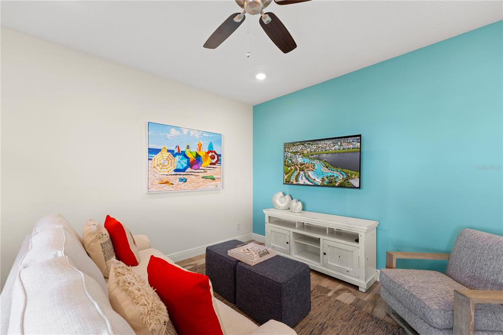 A living room features a blue accent wall, a television, a sofa, and an armchair — 8205 SURF STREET, KISSIMMEE, FL