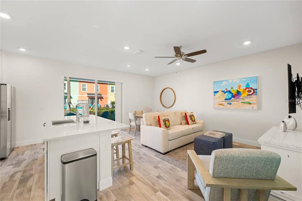 A bright living room features a white sofa, a kitchen island, and a sliding glass door — 8205 SURF STREET, KISSIMMEE, FL
