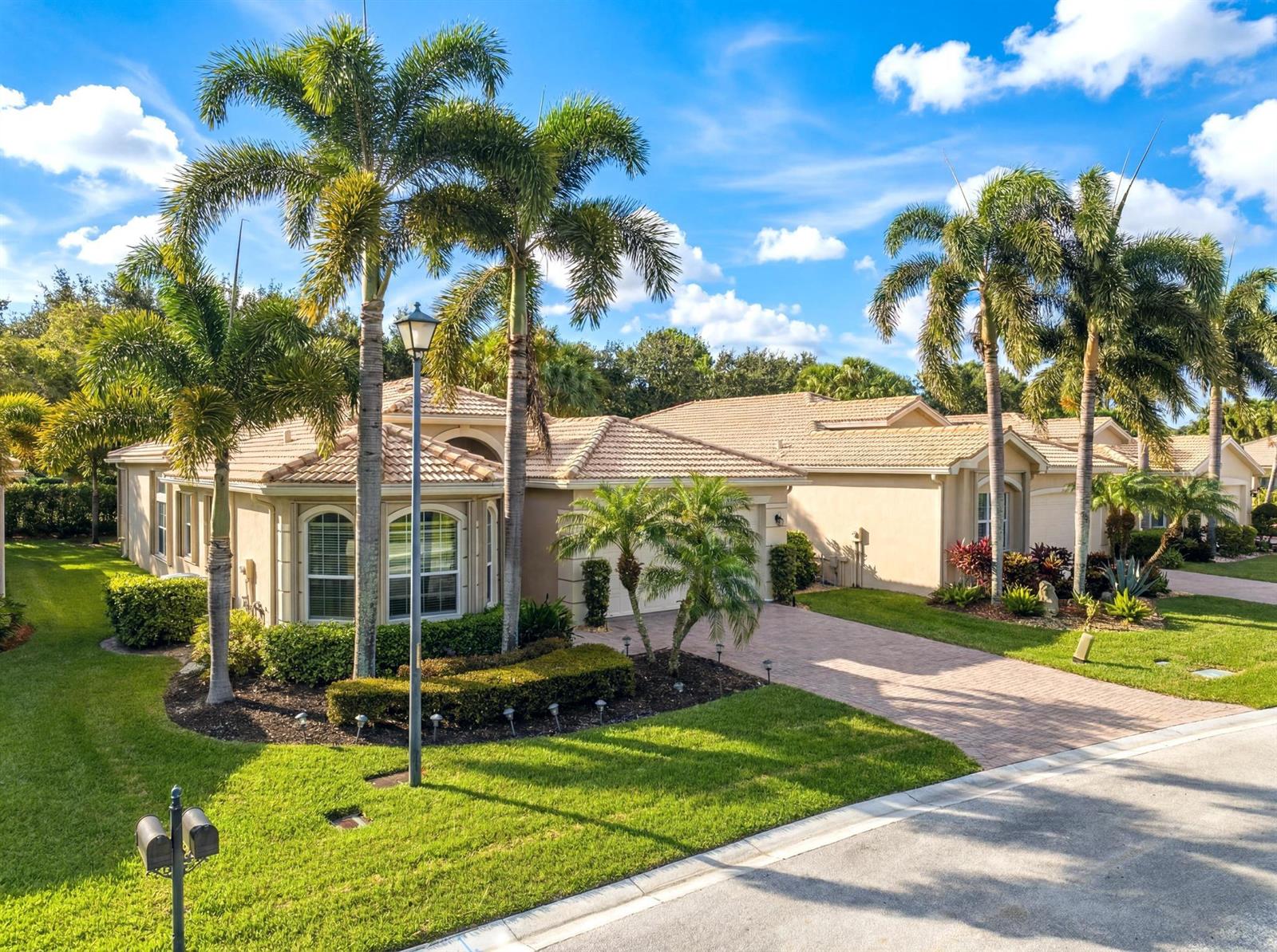 A single-story beige house with a tiled roof, palm trees, and a brick driveway — 10588 Stone Garden Drive, Boynton Beach FL 33473, BOYNTON BEACH, FL