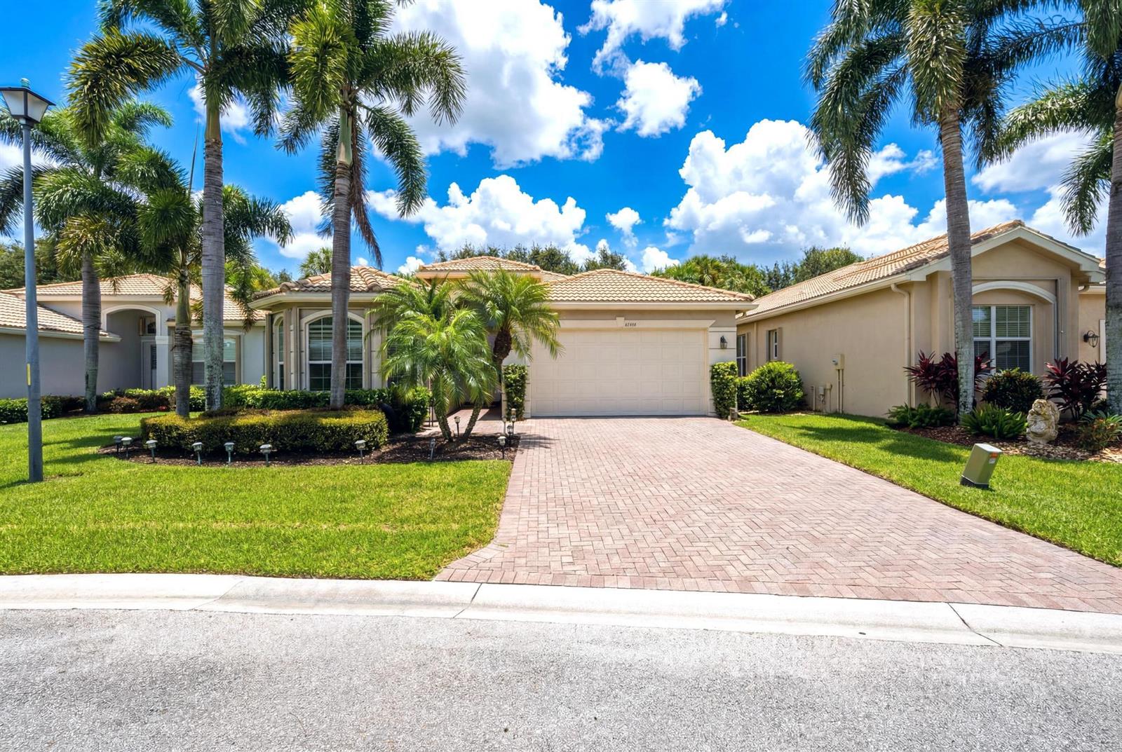 A single-story house with a paved driveway, palm trees, and a tan exterior — 10588 Stone Garden Drive, Boynton Beach FL 33473, BOYNTON BEACH, FL