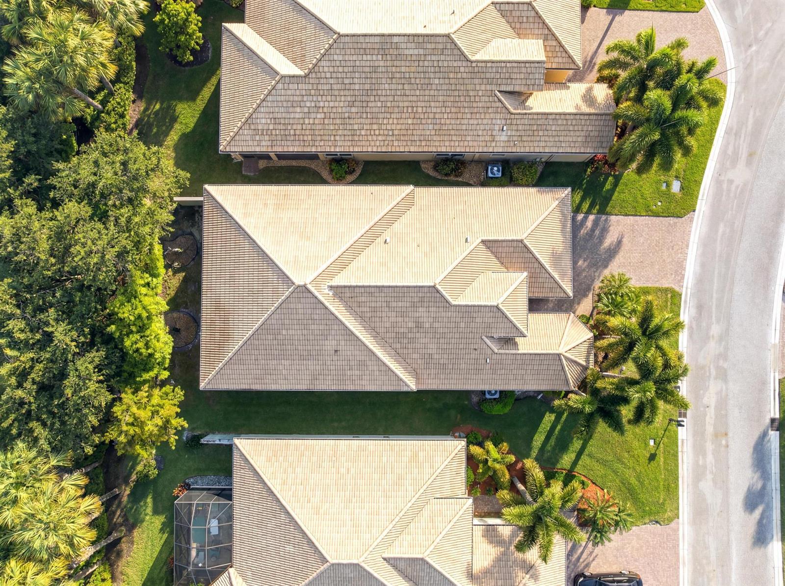 An aerial view shows the tiled roofs of three suburban houses surrounded by palm trees — 10588 Stone Garden Drive, Boynton Beach FL 33473, BOYNTON BEACH, FL