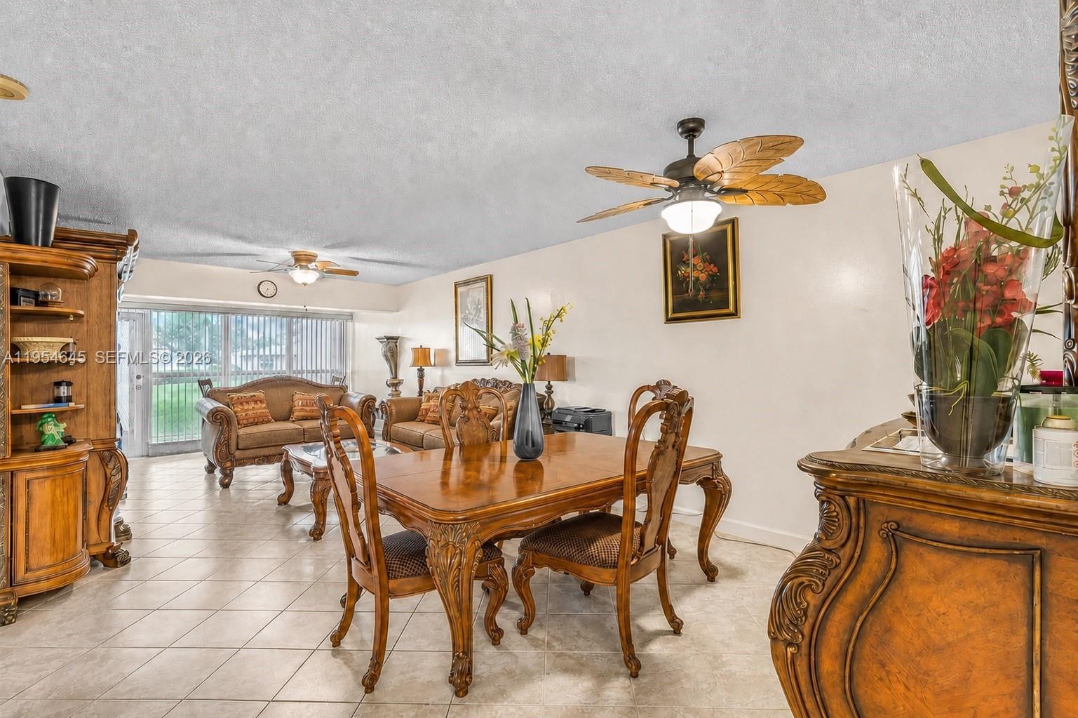 A dining area and living room with tile floors, wooden furniture, and ceiling fans — 1521 NW 18th AVE # 101, Delray Beach FL 33445, DELRAY BEACH, FL