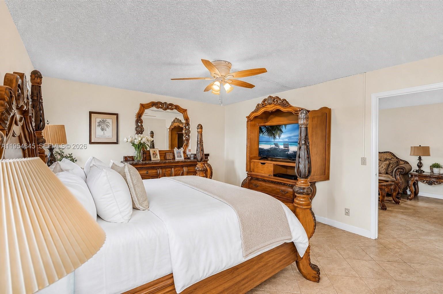 A bedroom features a wooden four-poster bed, matching furniture, and tile flooring — 1521 NW 18th AVE # 101, Delray Beach FL 33445, DELRAY BEACH, FL