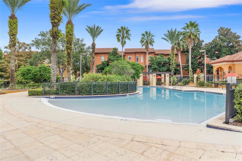 A swimming pool with a zero-entry edge is surrounded by palm trees and apartment buildings — 6135 METROWEST BOULEVARD UNIT 105, ORLANDO, FL