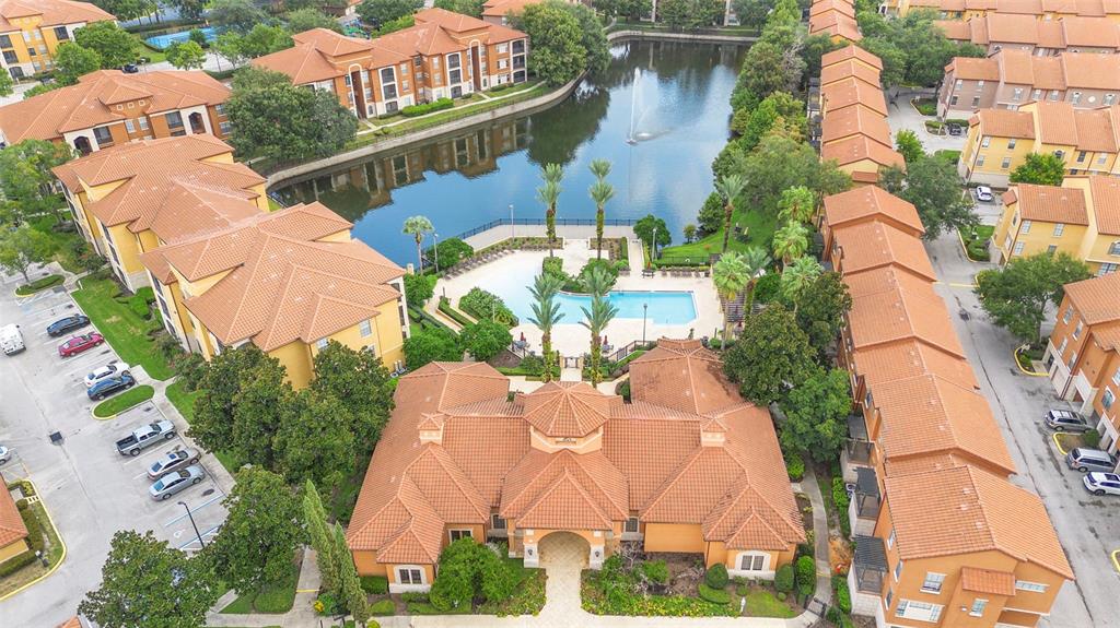 An aerial view shows a multi-story apartment complex with a central pool and lake — 6135 METROWEST BOULEVARD UNIT 105, ORLANDO, FL