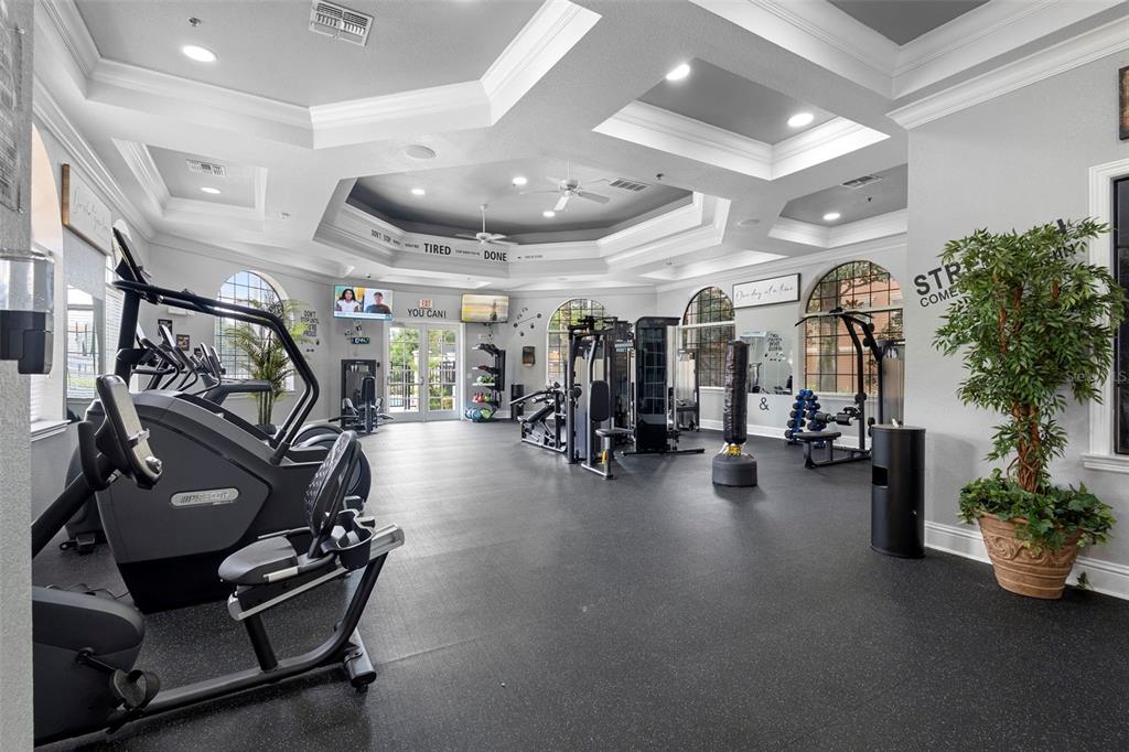 A spacious fitness center features various exercise machines, rubber flooring, and recessed tray ceilings — 6135 METROWEST BOULEVARD UNIT 105, ORLANDO, FL