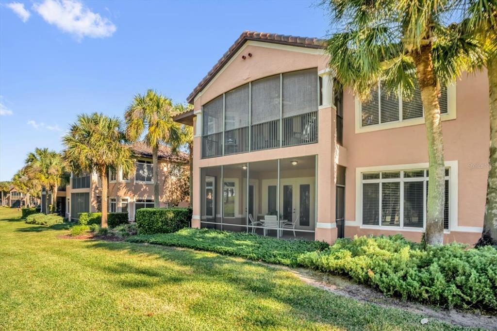 A two-story peach-colored building features screened-in balconies and patios overlooking a grassy lawn — 202 CAMINO REAL BOULEVARD UNIT 202, HOWEY IN THE HILLS, FL