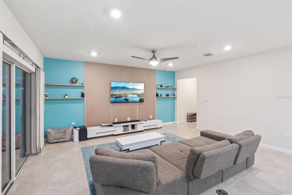 An open-concept living room and kitchen featuring white cabinetry, a large island, and sliding doors — 1643 DELIGHTFUL DRIVE, DAVENPORT, FL