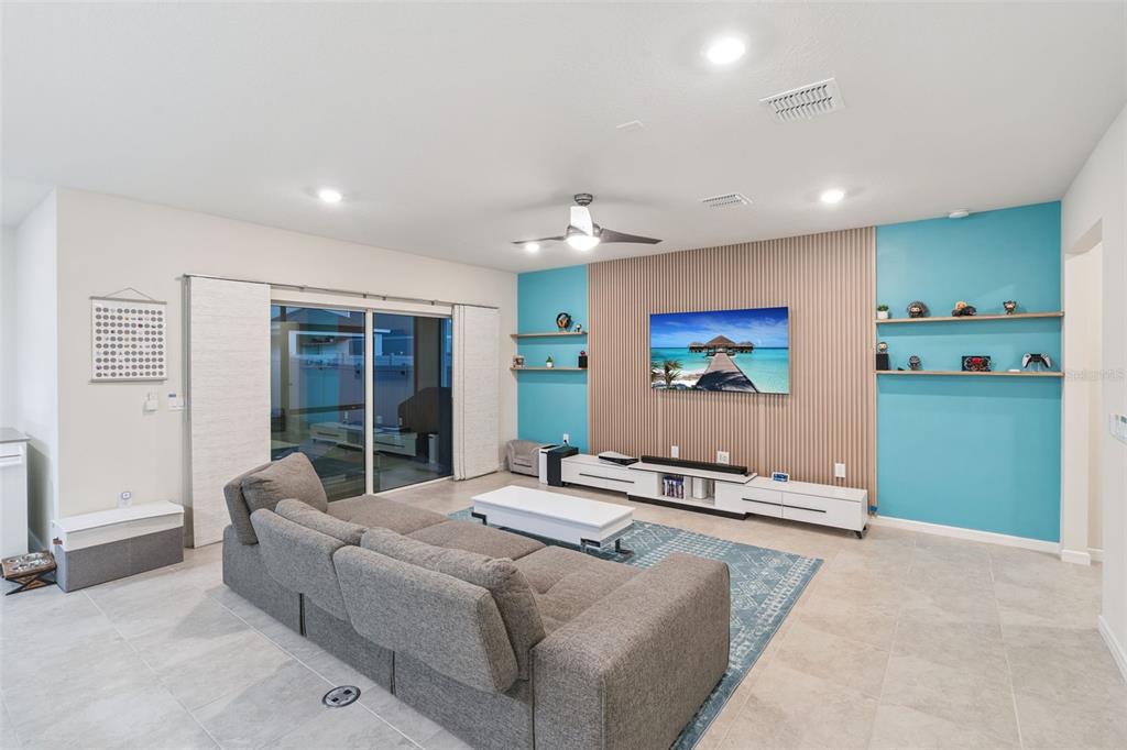 A living room features a blue accent wall with wood slats, shelving, and a sectional sofa — 1643 DELIGHTFUL DRIVE, DAVENPORT, FL