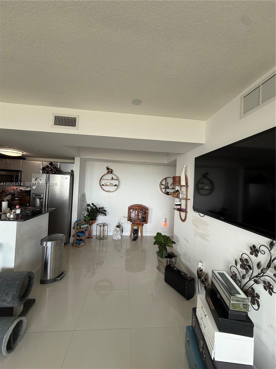 A living room with tile floors, a wall-mounted television, and decorative shelving — 1871 NW S River Dr # 1502, Miami FL 33125, MIAMI, FL