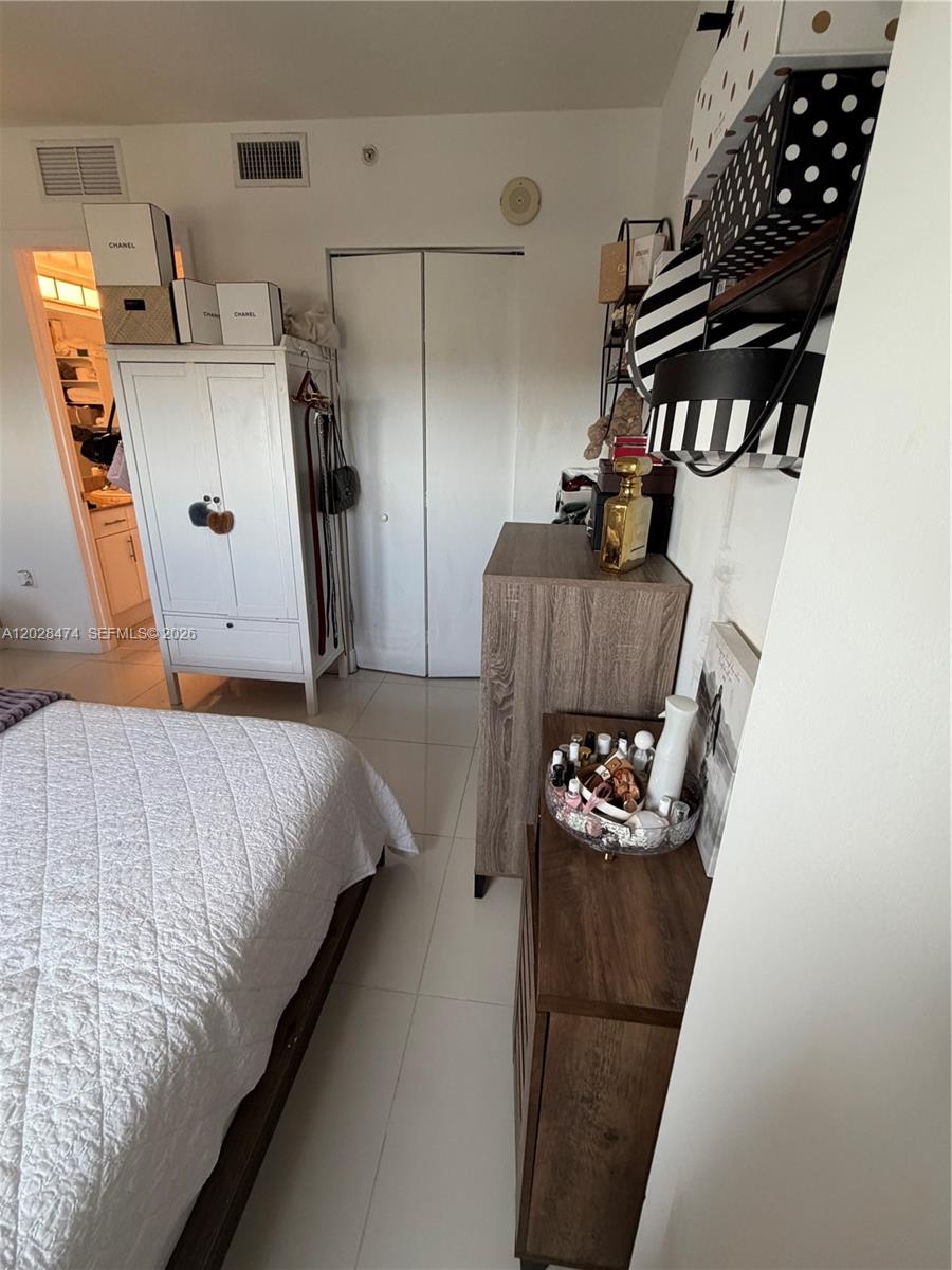 A bedroom features a white wardrobe, a wooden dresser, and a bed with white bedding — 1871 NW S River Dr # 1502, Miami FL 33125, MIAMI, FL