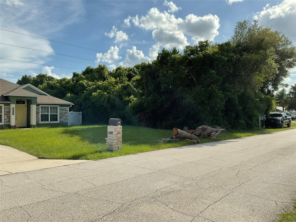 A grassy vacant lot sits next to a house with a stone-based mailbox and logs — 883 TRUMBULL STREET, DELTONA, FL