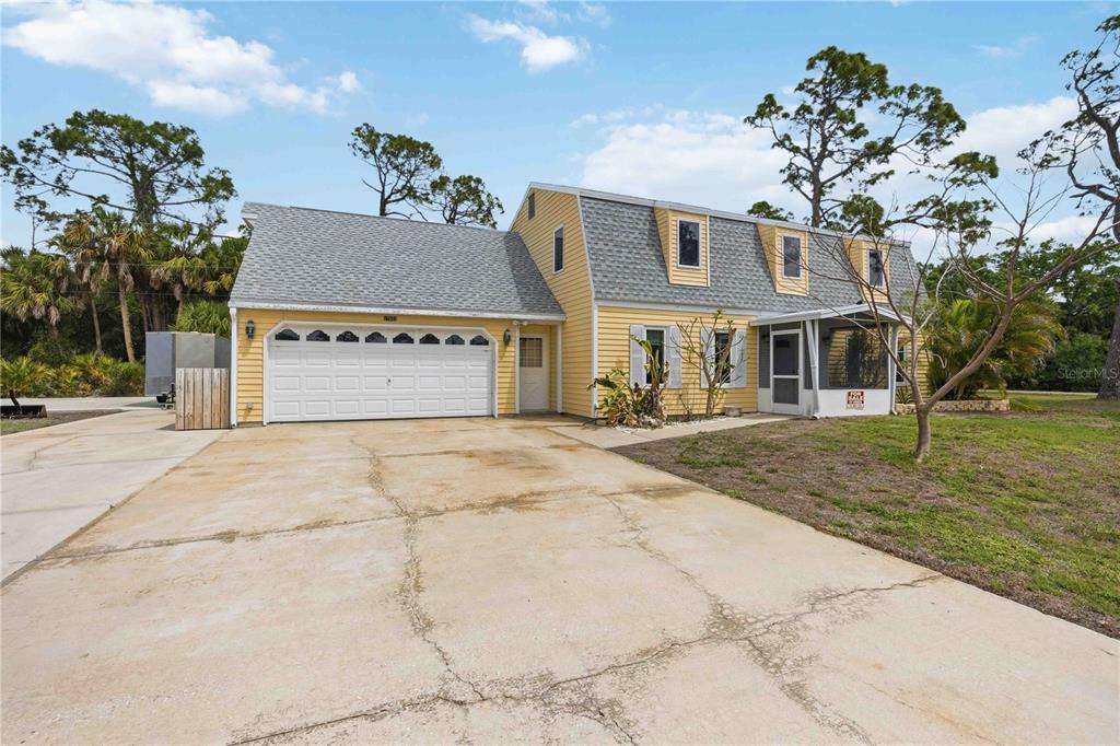 A yellow two-story house with a gambrel roof and an attached garage sits on a lot — 17402 BILLIAR AVENUE, PORT CHARLOTTE, FL