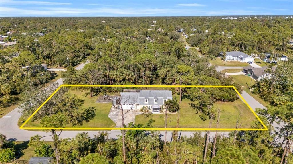 An aerial view shows a single-story house with a large yard surrounded by dense trees — 17402 BILLIAR AVENUE, PORT CHARLOTTE, FL