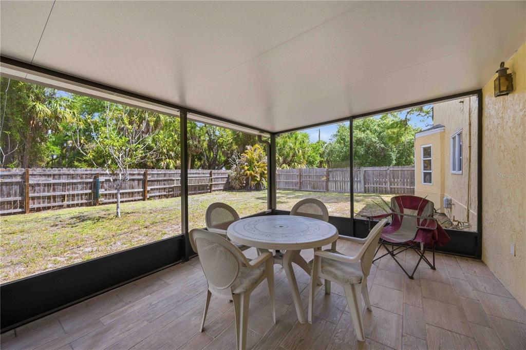 A screened-in patio features a round table with four chairs and tile flooring — 17402 BILLIAR AVENUE, PORT CHARLOTTE, FL