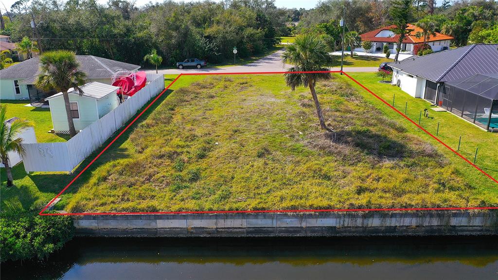 An aerial view of a vacant waterfront lot bordered by residential houses and a canal — 3454 YUKON DRIVE, PORT CHARLOTTE, FL