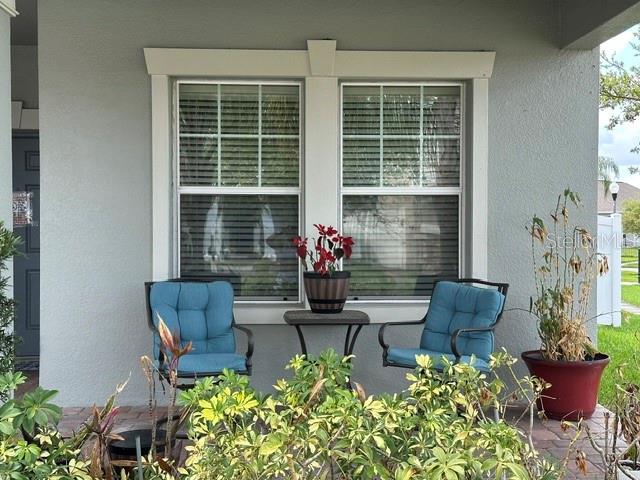 A covered front porch features two blue chairs, a small table, and potted plants — 14072 GOLD BRIDGE DRIVE, ORLANDO, FL