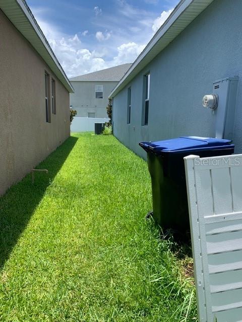 A narrow grassy side yard sits between two houses with a blue trash bin nearby — 14072 GOLD BRIDGE DRIVE, ORLANDO, FL