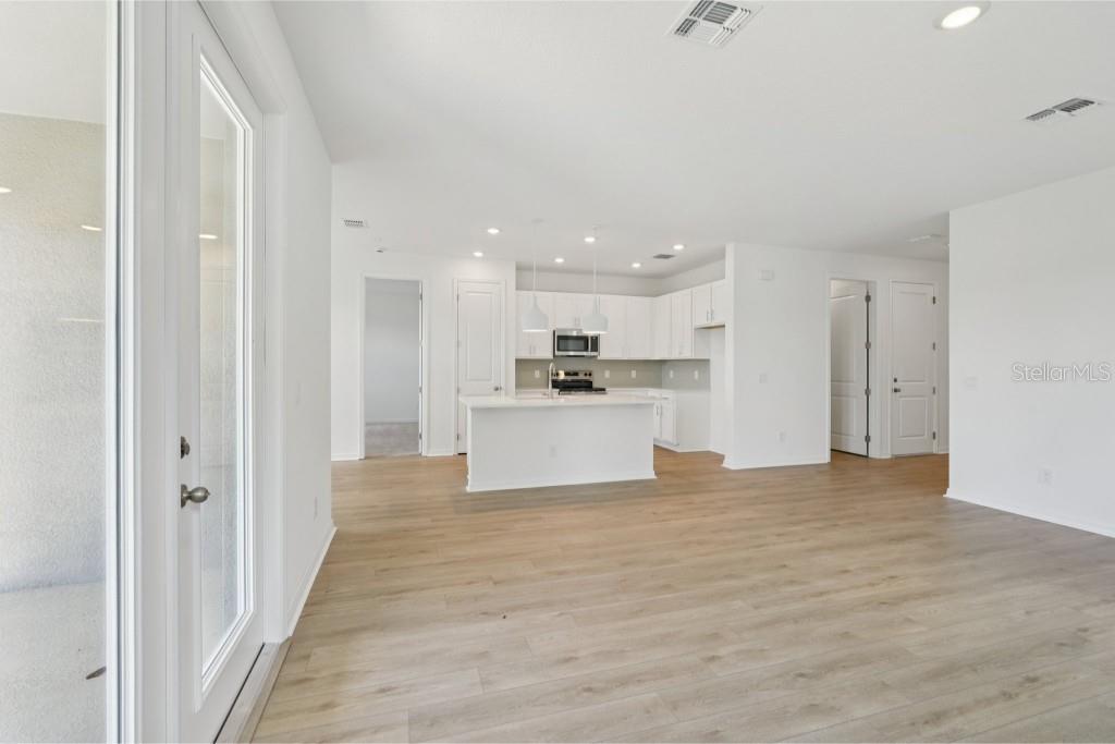 An open-concept kitchen with white cabinets and an island overlooks a spacious living area — 30135 EMERALD FOREST DRIVE, MOUNT DORA, FL
