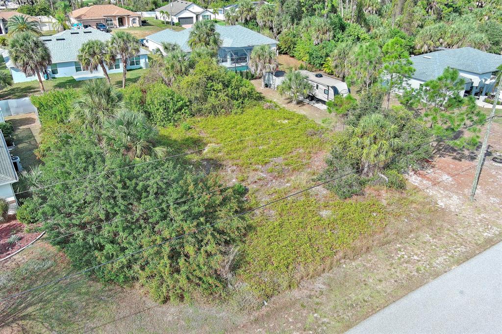 An aerial view shows a vacant, overgrown residential lot situated between several suburban houses — SADNET LANE, NORTH PORT, FL