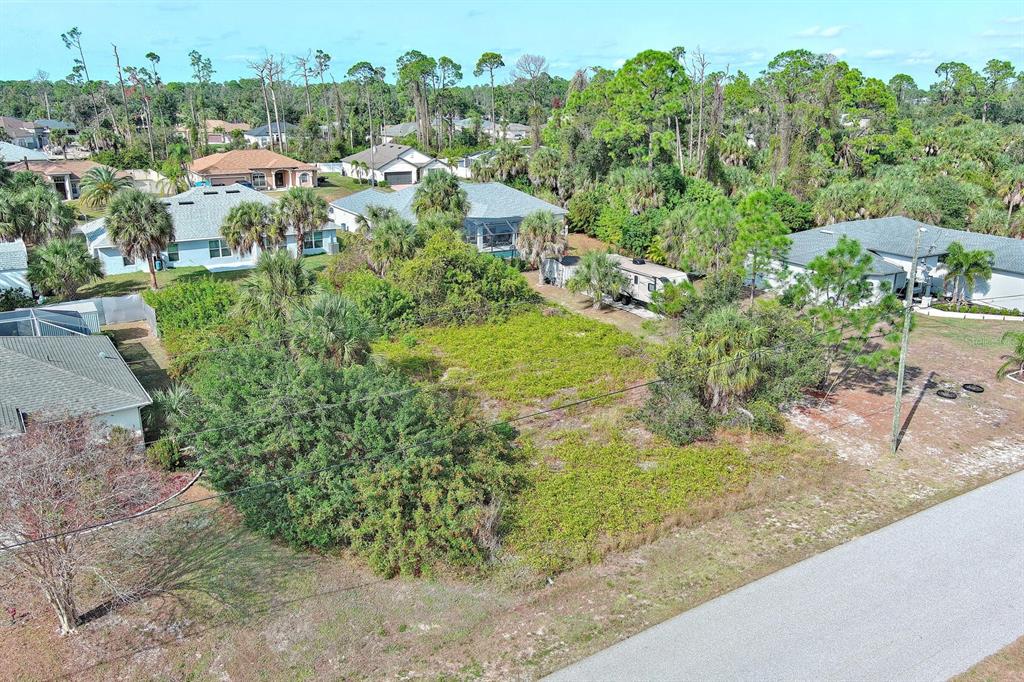 An aerial view shows a vacant, overgrown residential lot situated between several suburban houses — SADNET LANE, NORTH PORT, FL