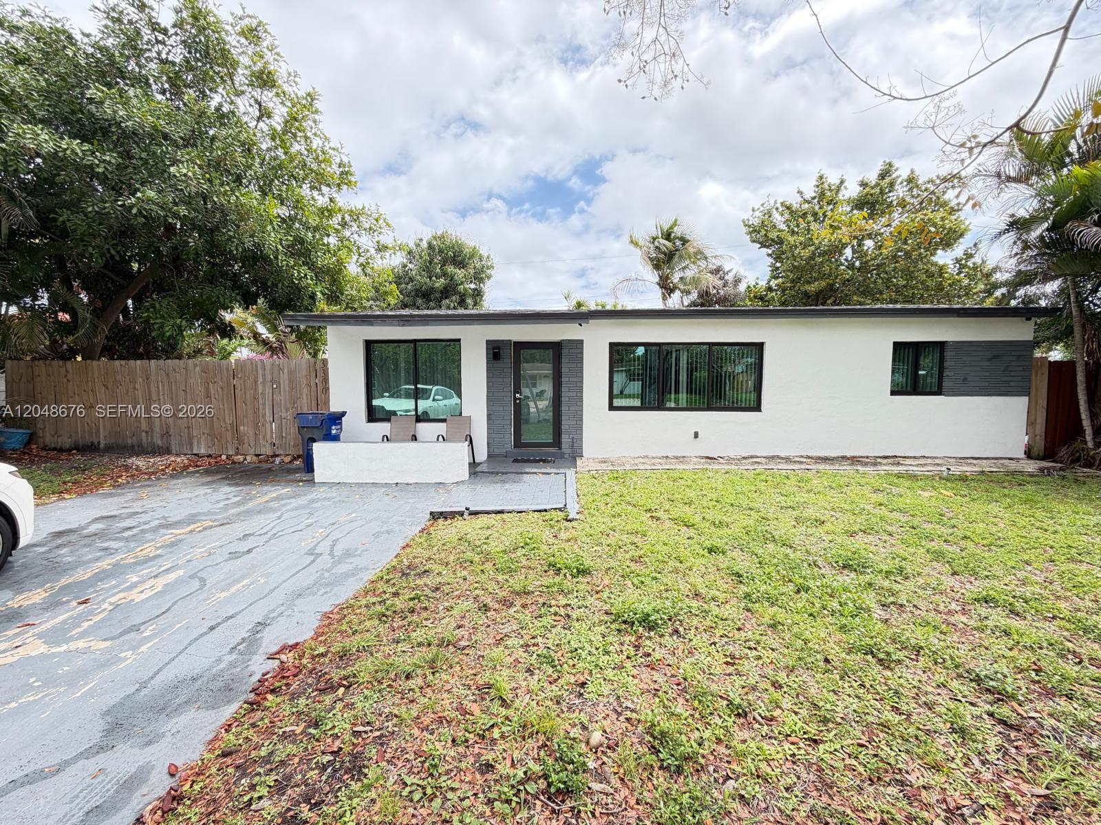 A single-story house with white stucco walls, dark gray brick accents, and black-framed windows — 3360 NE 12th Ter, Pompano Beach FL 33064, POMPANO BEACH, FL
