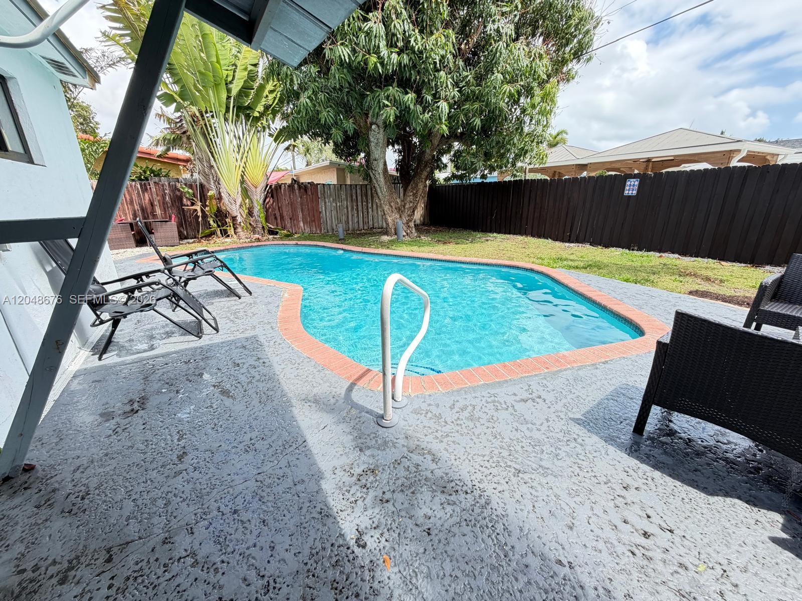 A single-story white house with a gray driveway, front lawn, and dark-framed windows — 3360 NE 12th Ter, Pompano Beach FL 33064, POMPANO BEACH, FL