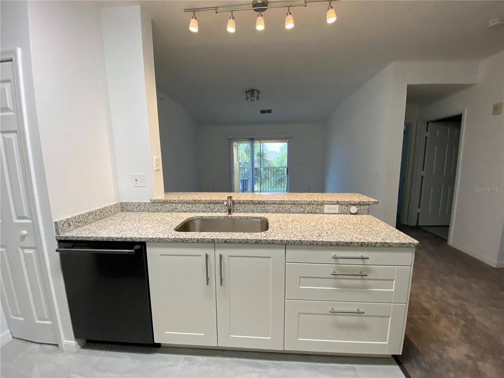 A kitchen sink area features white cabinets, granite countertops, and a black dishwasher — 5455 VINELAND ROAD UNIT 3310, ORLANDO, FL