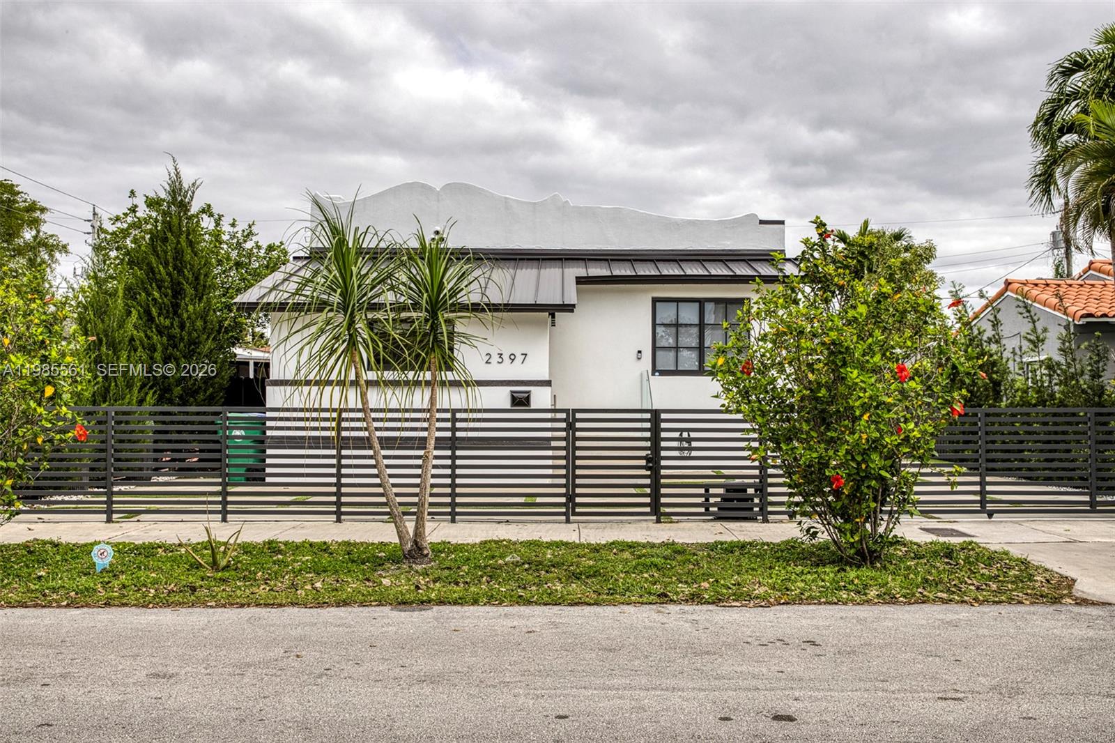 A white single-story house with a metal roof and a black horizontal slat fence — 2397 SW 13th St, Miami FL 33145, MIAMI, FL