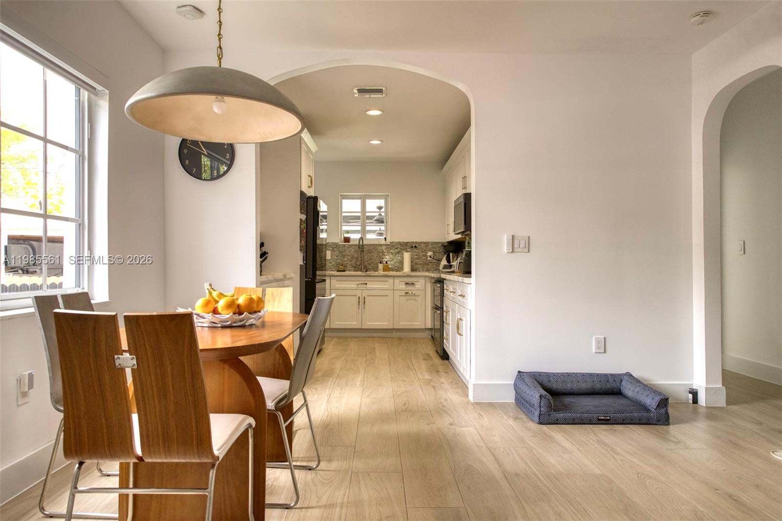 A dining area with a wooden table and chairs leads into a white kitchen — 2397 SW 13th St, Miami FL 33145, MIAMI, FL