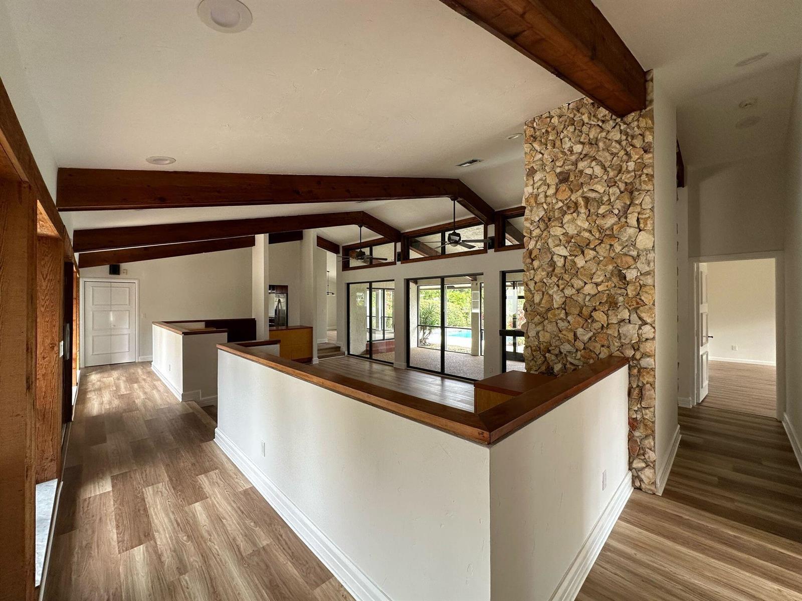 A living area features vaulted ceilings with exposed wood beams and a large stone fireplace — 7243 Encina Lane, Boca Raton FL 33433, BOCA RATON, FL