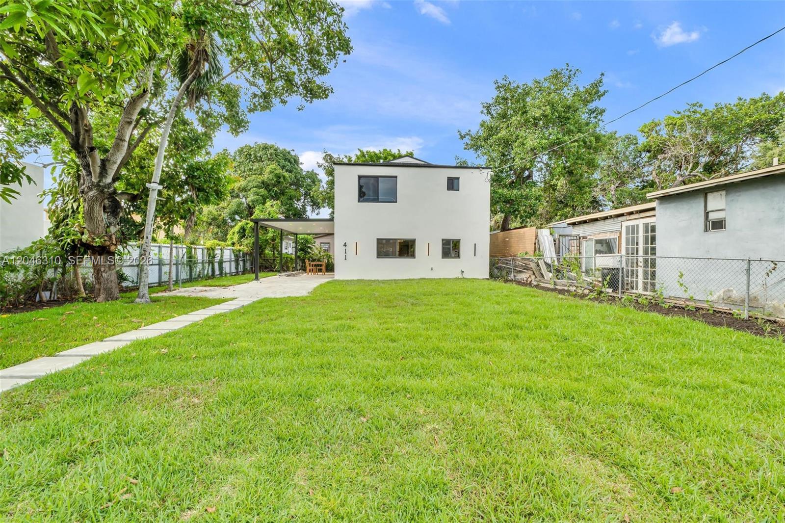 A two-story white house with a flat roof stands behind a large grassy yard — 411 NW 59th St, Miami FL 33127, MIAMI, FL