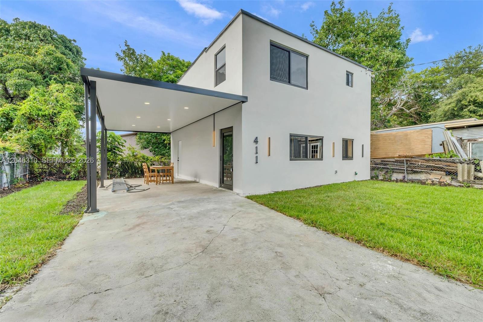 A two-story white house features a covered carport and a concrete driveway — 411 NW 59th St, Miami FL 33127, MIAMI, FL