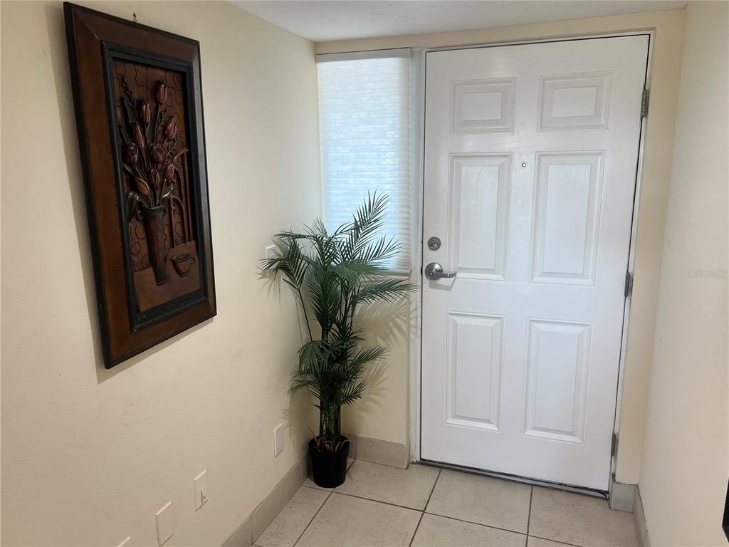 An entryway features a white door, a potted plant, and a framed floral wall art — 1001 POINT OF ROCKS ROAD UNIT 609, SARASOTA, FL