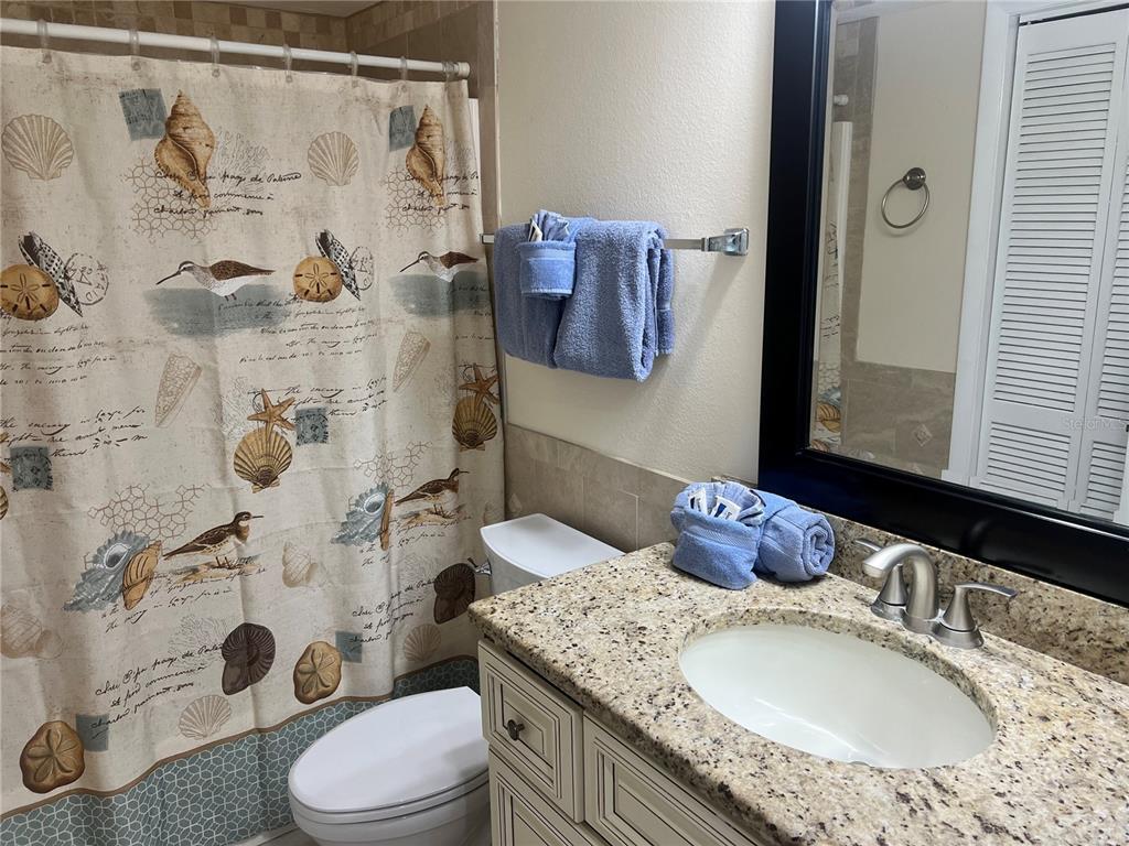 A bathroom features a granite vanity, a blue towel set, and a coastal-themed shower curtain — 1001 POINT OF ROCKS ROAD UNIT 609, SARASOTA, FL