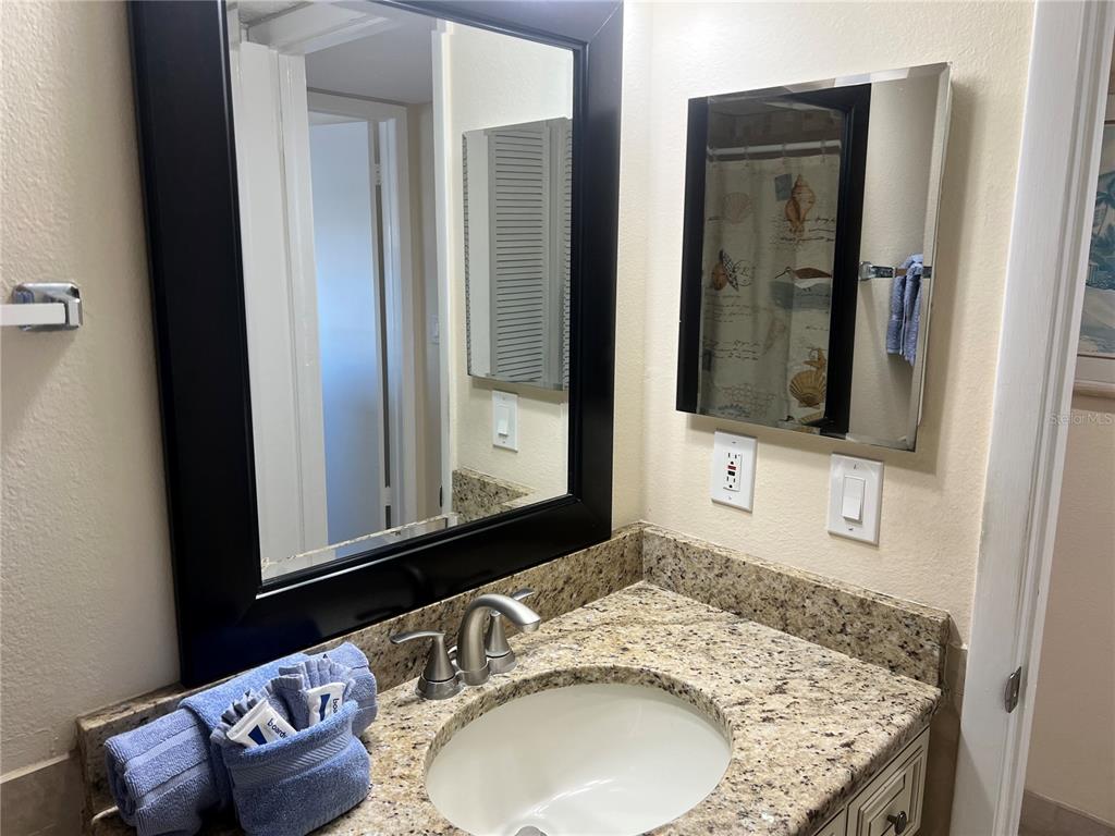 A bathroom vanity features a granite countertop, a sink, and two mirrors on the wall — 1001 POINT OF ROCKS ROAD UNIT 609, SARASOTA, FL