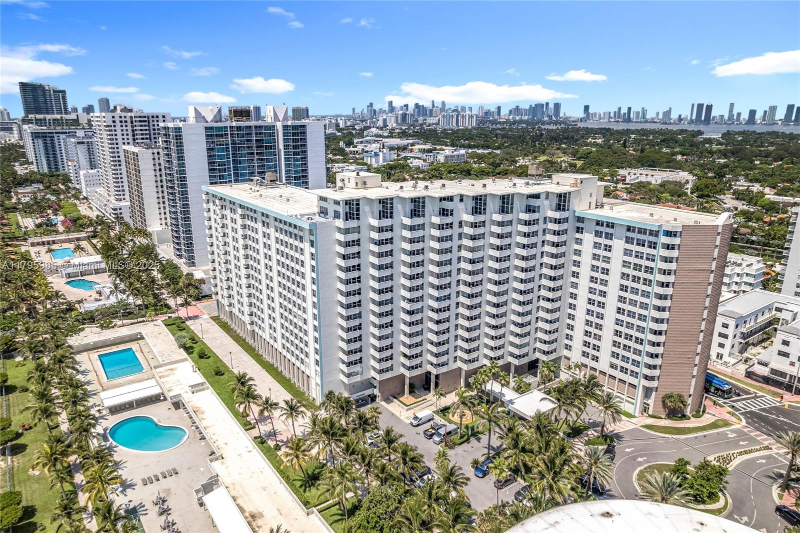 An aerial view shows a large white residential building with balconies, swimming pools, and palm trees — 2899 Collins Ave # 1218, Miami Beach FL 33140, MIAMI BEACH, FL