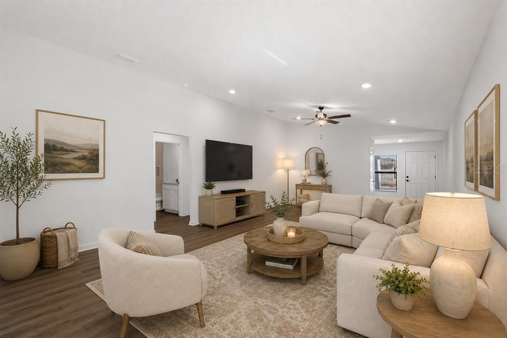 A living room with white walls, a sectional sofa, a round coffee table, and wood flooring — 8338 CORAL STREET, SPRING HILL, FL