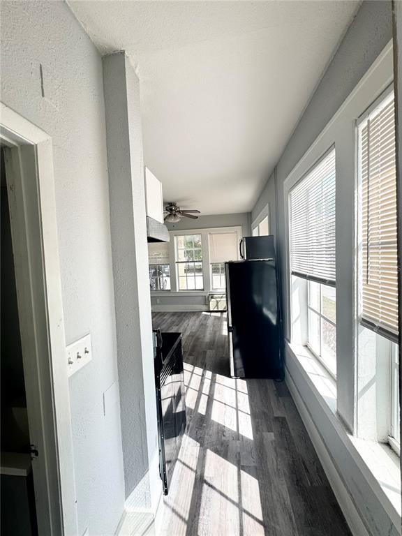 A narrow, light-filled kitchen features gray wood-look flooring, white walls, and a black refrigerator — 704 CORDOVA DRIVE UNIT 1, ORLANDO, FL