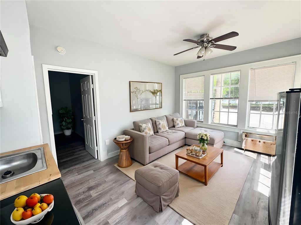 A living room features a gray sectional sofa, a wooden coffee table, and light wood-look flooring — 704 CORDOVA DRIVE UNIT 1, ORLANDO, FL