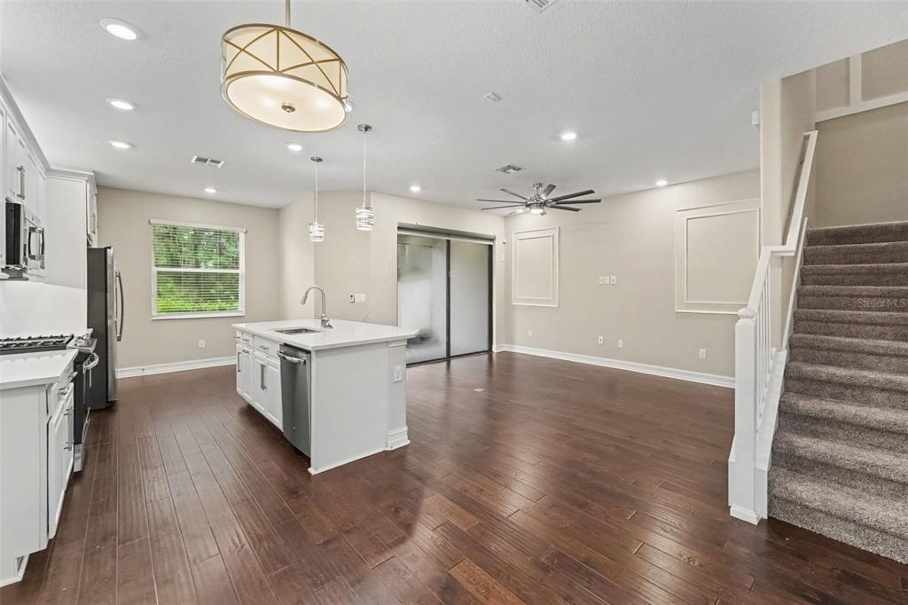 An open-concept kitchen and living area features white cabinetry, a center island, and hardwood floors — 5150 SAN MARTINO DRIVE, WESLEY CHAPEL, FL