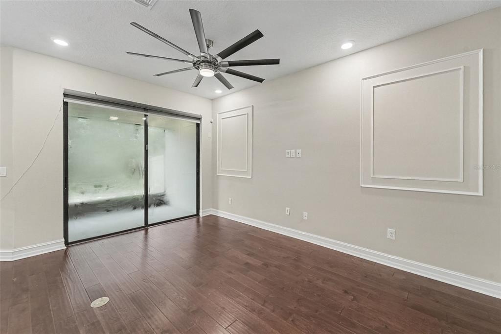 An empty room with dark wood flooring, a ceiling fan, and decorative wall molding — 5150 SAN MARTINO DRIVE, WESLEY CHAPEL, FL