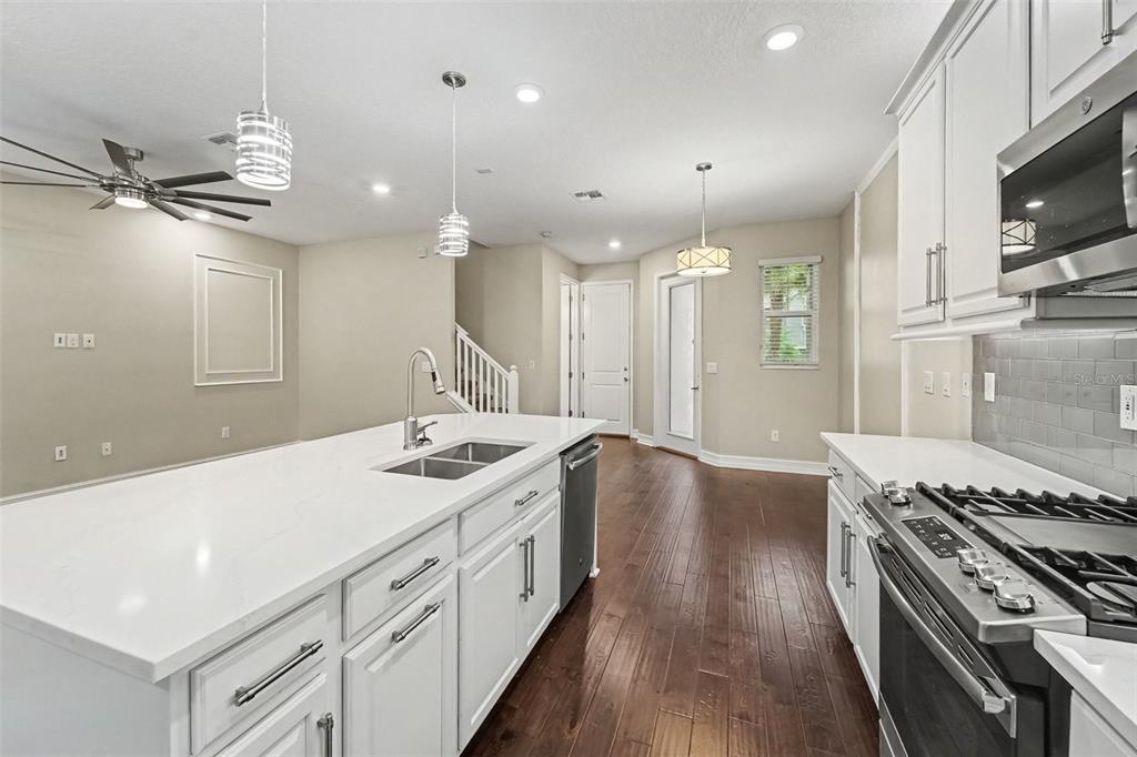A kitchen with white cabinets, a large island, stainless steel appliances, and dark wood floors — 5150 SAN MARTINO DRIVE, WESLEY CHAPEL, FL