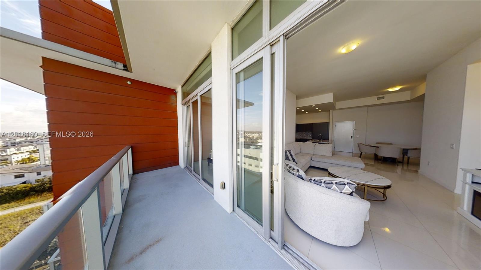 A balcony with wood-paneled walls overlooks a living room with tile floors and glass doors — 7825 NW 107th Ave # 821, Doral FL 33178, DORAL, FL