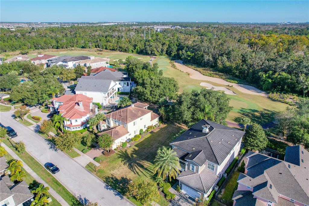 An aerial view shows several large houses situated along a street next to a golf course — 7455 GATHERING DRIVE, KISSIMMEE, FL