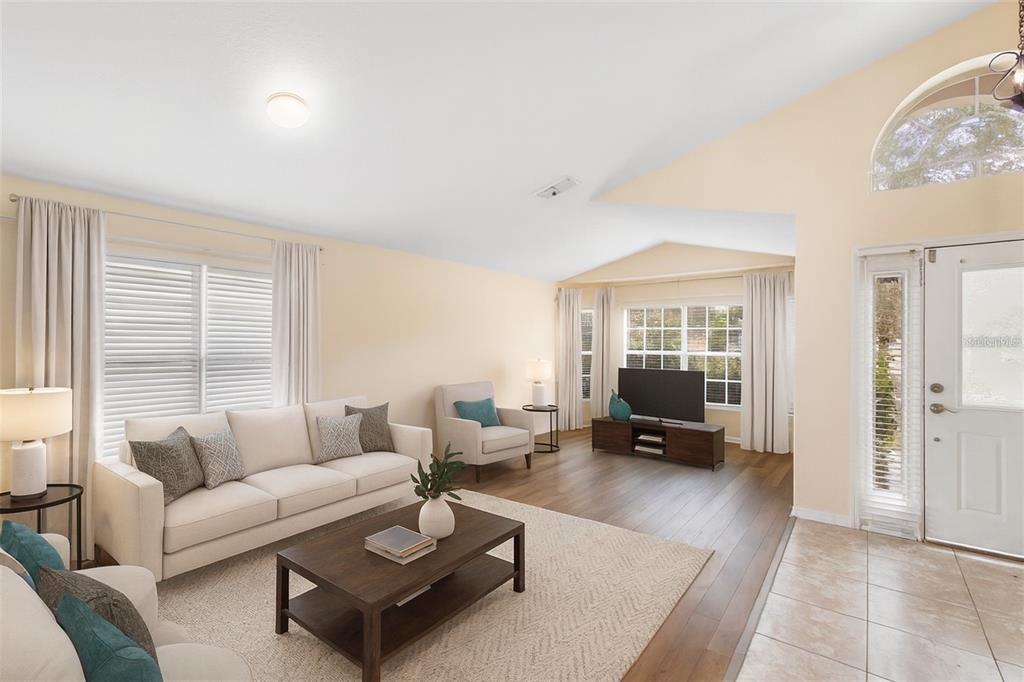 A living room features light walls, wood flooring, a white sofa, and a television console — 3152 WOOD ROSE WAY, DELTONA, FL