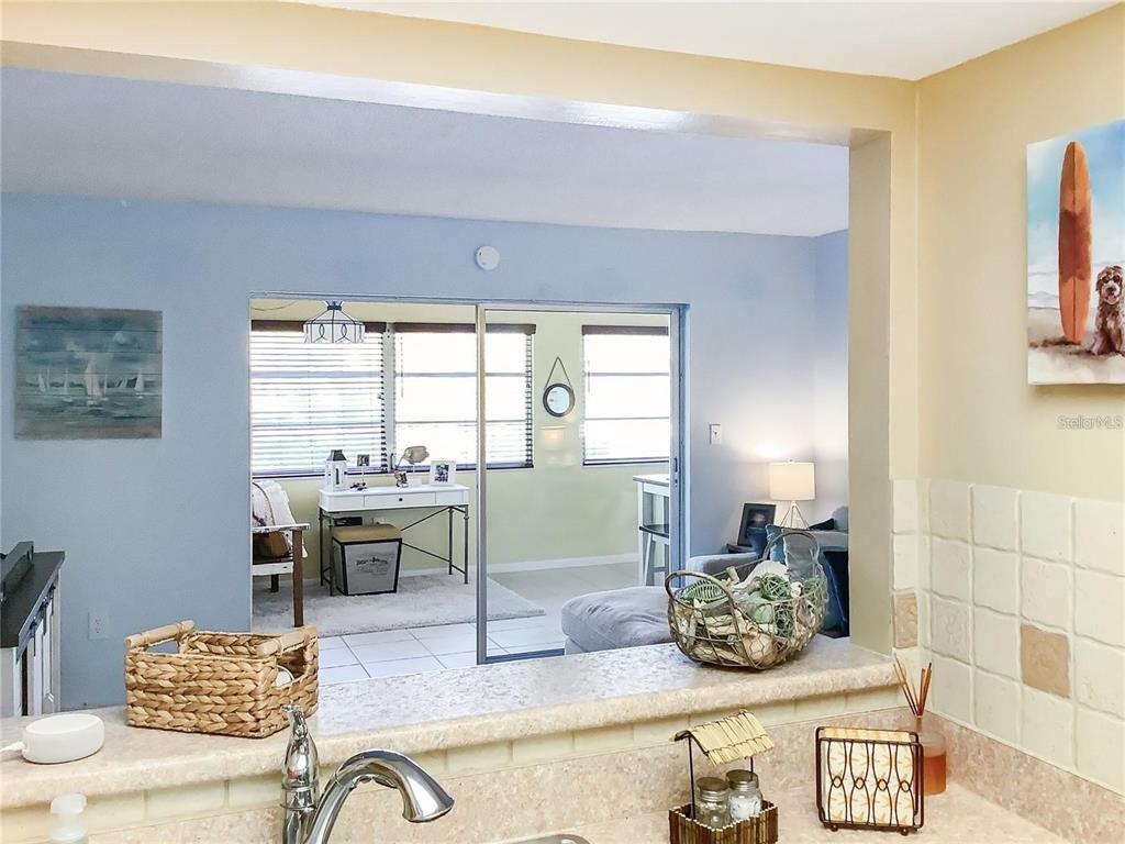 A kitchen counter overlooks a living area with a sliding glass door and desk — 4736 JASPER DRIVE UNIT 207, NEW PORT RICHEY, FL