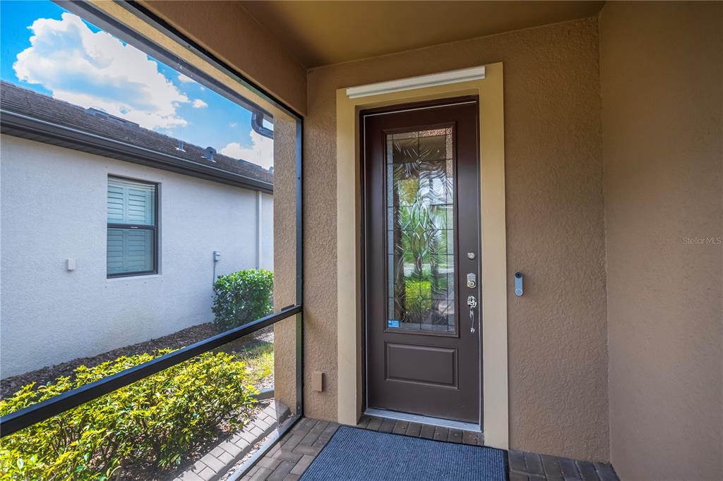A brown front door with a decorative glass insert sits on a screened-in porch — 2475 BRASSICA DRIVE, NORTH PORT, FL