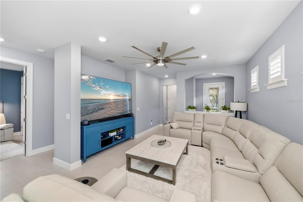 A living room features a large sectional sofa, a coffee table, and a blue media console — 2475 BRASSICA DRIVE, NORTH PORT, FL